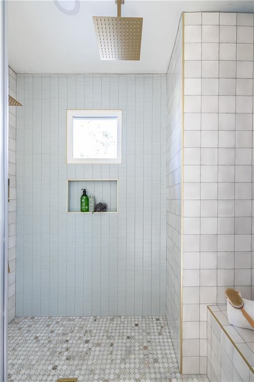 bathroom featuring tile patterned floors, a tile shower, and tile walls