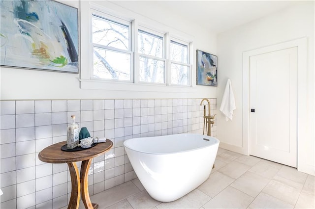 bathroom with tile patterned floors, a bathing tub, and tile walls