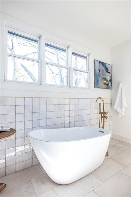 bathroom with tile patterned flooring, a tub to relax in, and tile walls