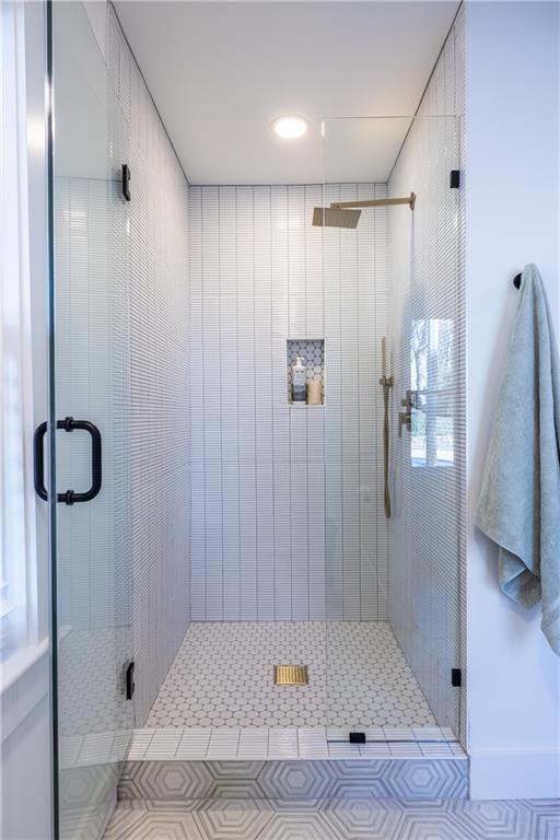 bathroom with a shower with door and tile patterned flooring