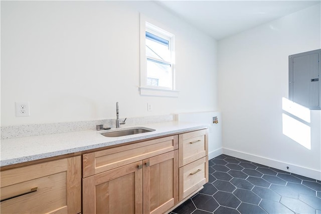 laundry area with electric panel, sink, dark tile patterned floors, and cabinets