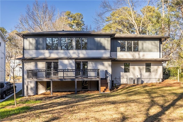 back of property with a deck, central AC unit, and a lawn