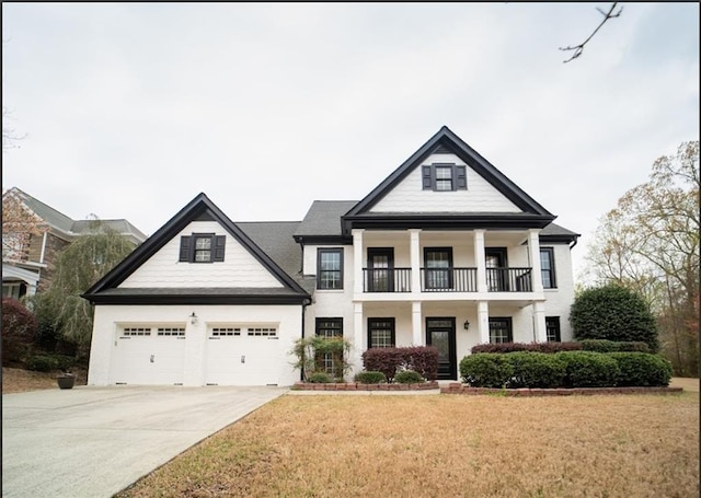 neoclassical home featuring a balcony, driveway, a front lawn, a garage, and covered porch