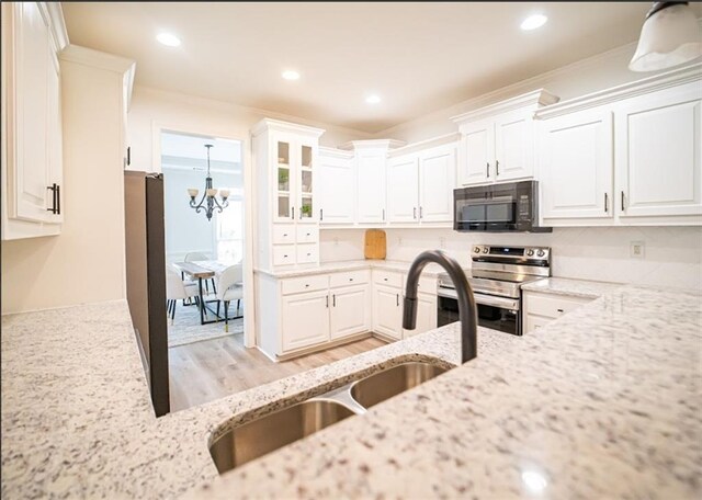 kitchen featuring black microwave, electric stove, a sink, light stone counters, and white cabinets