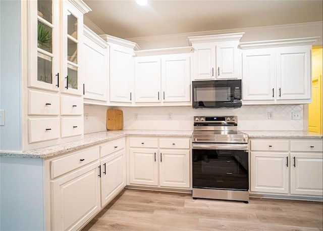 kitchen with black microwave, stainless steel electric range oven, white cabinetry, light wood-type flooring, and crown molding