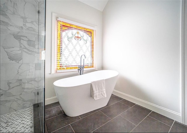 full bathroom with a marble finish shower, a freestanding bath, baseboards, and tile patterned floors