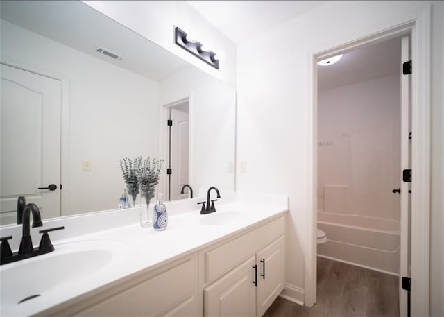 full bath with wood finished floors, toilet, and double vanity