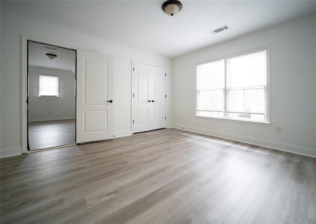 unfurnished bedroom with wood finished floors, baseboards, and a closet
