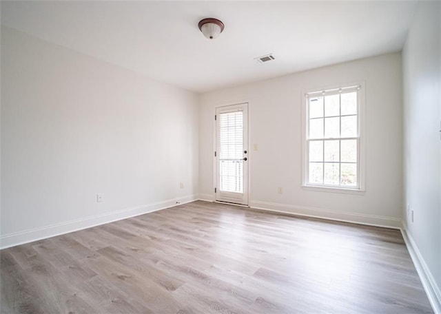 empty room with wood finished floors, plenty of natural light, and baseboards