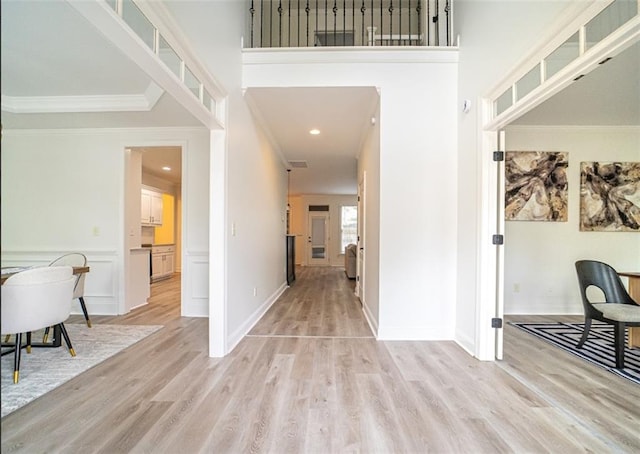 foyer with light wood-type flooring, crown molding, a towering ceiling, baseboards, and recessed lighting