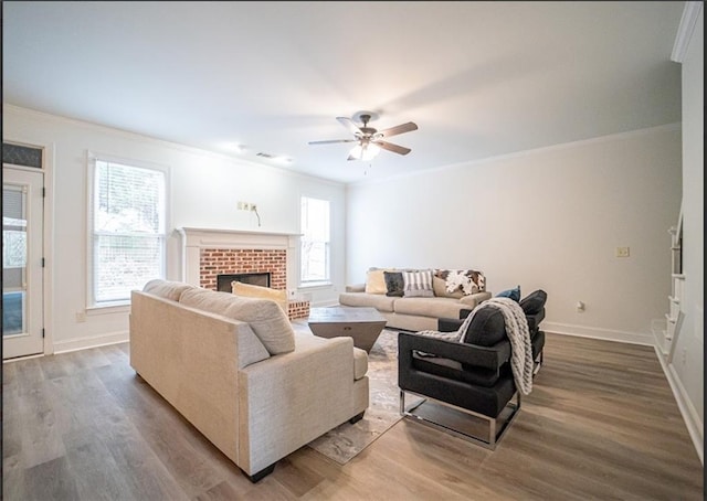 living area featuring ornamental molding, wood finished floors, ceiling fan, baseboards, and a fireplace