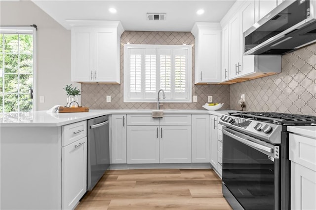 kitchen with stainless steel appliances, white cabinetry, light wood finished floors, light countertops, and recessed lighting