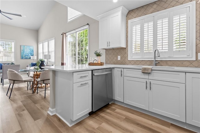 kitchen featuring dishwasher, a sink, light countertops, light wood finished floors, and white cabinetry