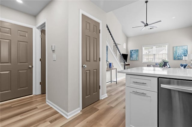 kitchen with stainless steel dishwasher, white cabinetry, light wood-style flooring, and light countertops