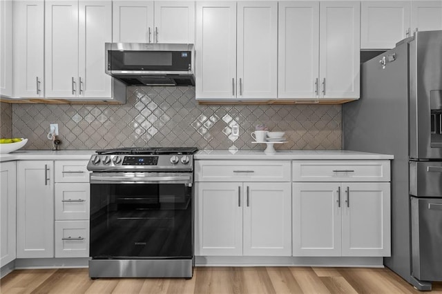 kitchen featuring appliances with stainless steel finishes, light countertops, white cabinets, and decorative backsplash