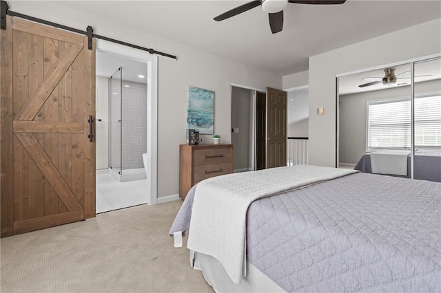 bedroom featuring a barn door, light carpet, ceiling fan, and ensuite bath