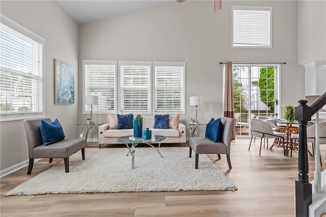 living area with high vaulted ceiling, light wood-style flooring, plenty of natural light, and baseboards