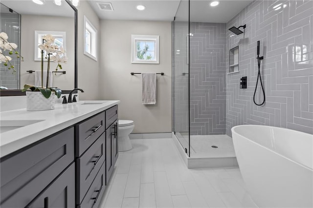 full bathroom featuring double vanity, tiled shower, a freestanding bath, toilet, and tile patterned flooring