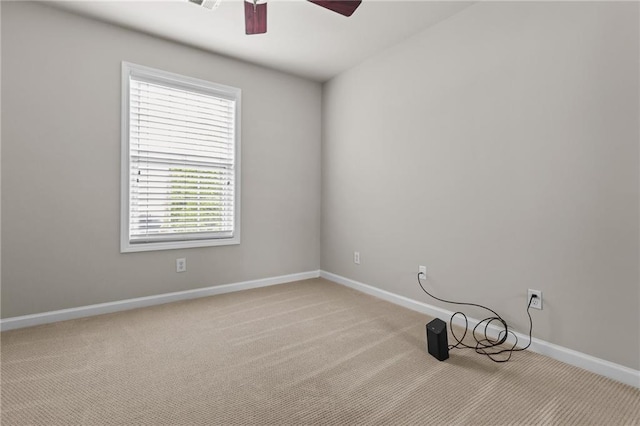 unfurnished room with a ceiling fan, baseboards, and light colored carpet
