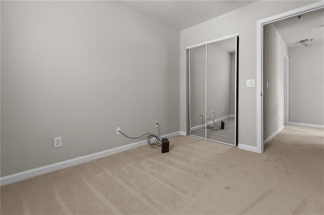 unfurnished bedroom featuring light carpet, a closet, and baseboards