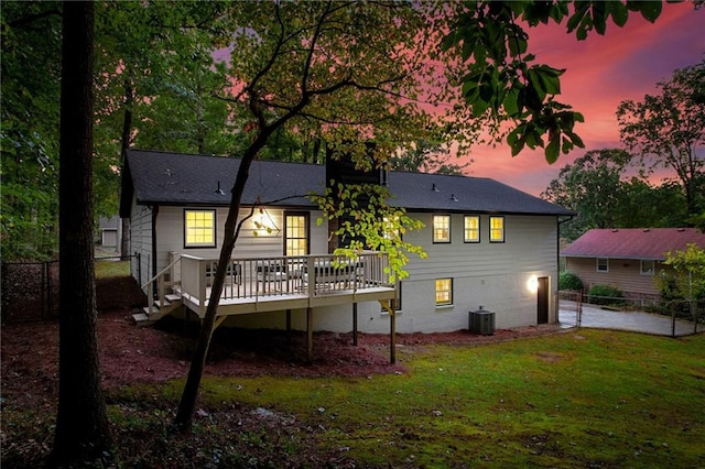 back house at dusk featuring a deck and a yard