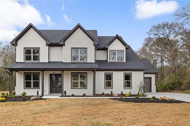 view of front of home featuring a garage, a porch, concrete driveway, and brick siding