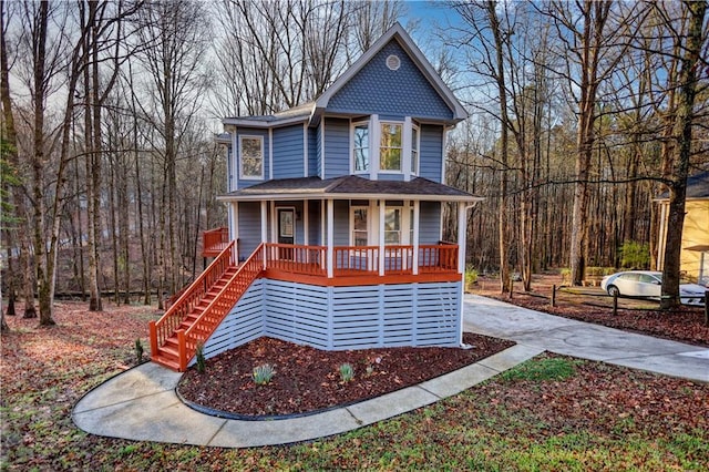 view of front facade featuring covered porch, a wooded view, and stairs