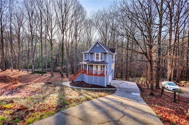 view of front of property with stairway, a view of trees, covered porch, and driveway