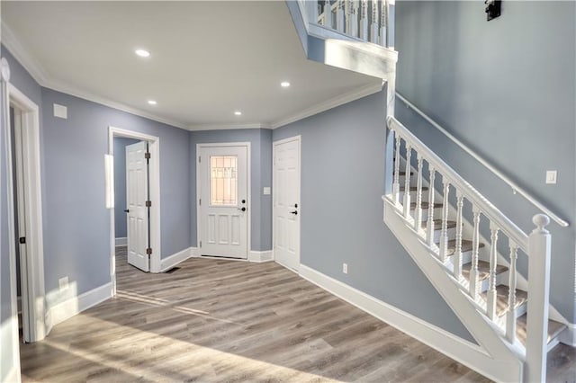 entrance foyer with stairs, baseboards, wood finished floors, and crown molding