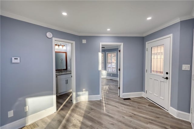 foyer entrance with recessed lighting, crown molding, baseboards, and wood finished floors