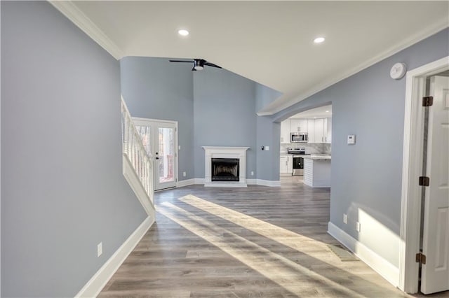 unfurnished living room with a fireplace with raised hearth, crown molding, baseboards, light wood-style flooring, and recessed lighting