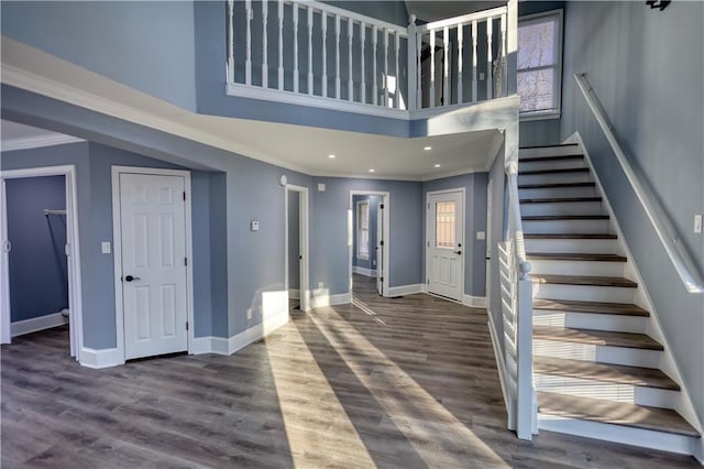 foyer with stairway, wood finished floors, baseboards, and ornamental molding