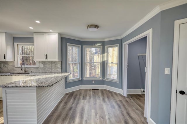 kitchen featuring white cabinetry, tasteful backsplash, baseboards, and a sink