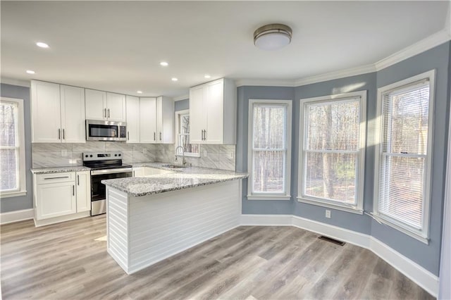 kitchen featuring light stone counters, white cabinets, appliances with stainless steel finishes, and a sink