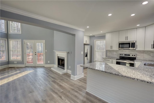 kitchen featuring decorative backsplash, appliances with stainless steel finishes, ornamental molding, and white cabinets