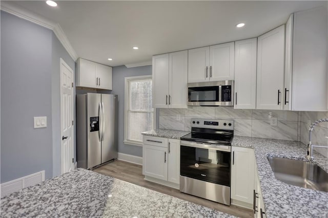 kitchen featuring tasteful backsplash, appliances with stainless steel finishes, white cabinetry, and a sink