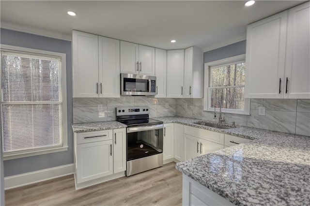 kitchen with light wood-style flooring, appliances with stainless steel finishes, white cabinetry, and a sink