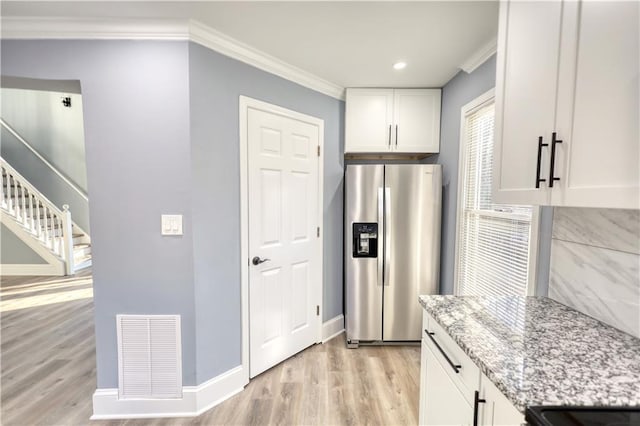 kitchen featuring stainless steel fridge with ice dispenser, visible vents, light stone countertops, and ornamental molding