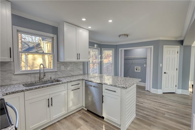 kitchen with white cabinetry, a peninsula, a sink, dishwasher, and crown molding