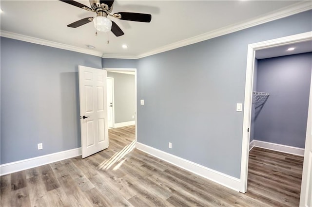 unfurnished room with ornamental molding, a ceiling fan, baseboards, and wood finished floors