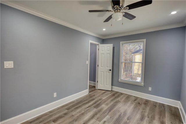 spare room with crown molding, recessed lighting, wood finished floors, and baseboards