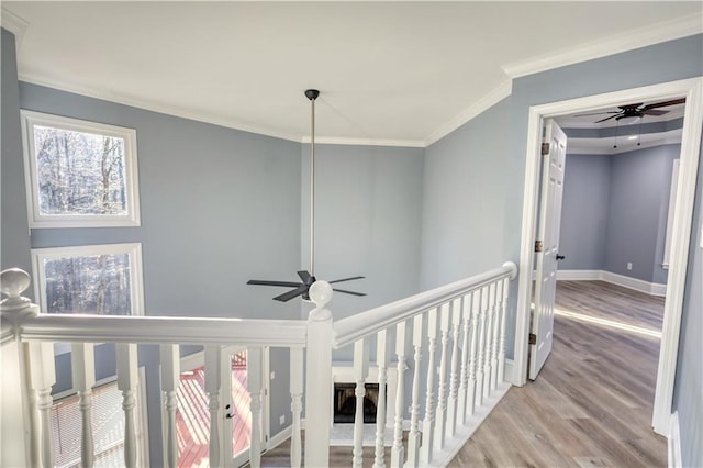 hall featuring an upstairs landing, crown molding, baseboards, and wood finished floors