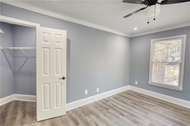 unfurnished bedroom with crown molding, wood finished floors, baseboards, and a closet