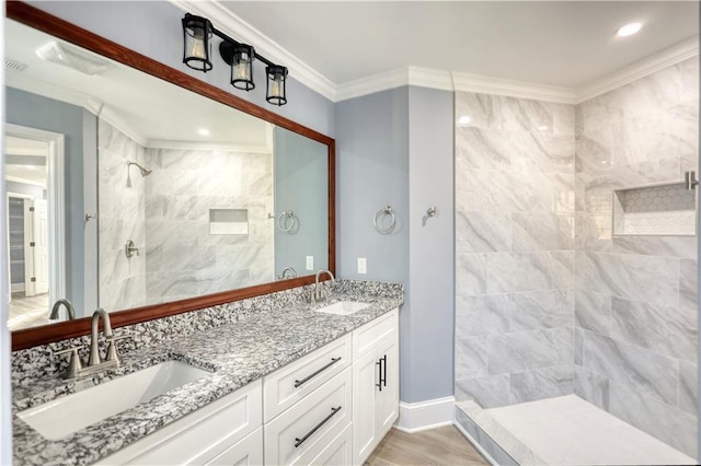 full bathroom with a sink, tiled shower, ornamental molding, and double vanity