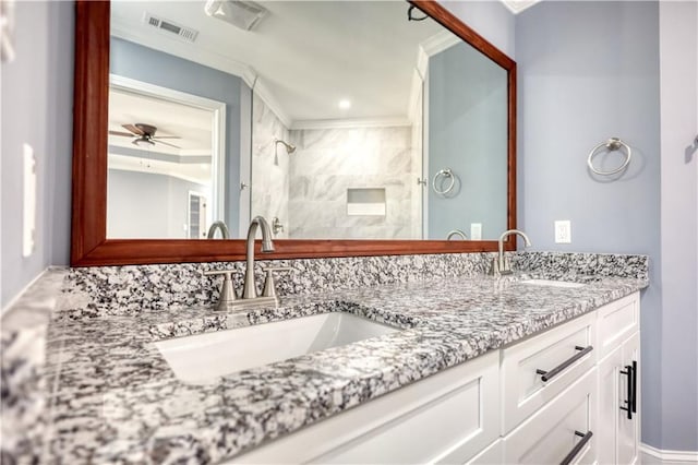 bathroom with double vanity, tiled shower, visible vents, and a sink