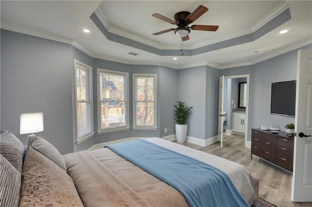 bedroom featuring a tray ceiling, visible vents, ornamental molding, and light wood finished floors