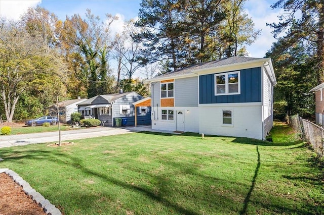 view of front of home with board and batten siding, fence, driveway, and a front lawn