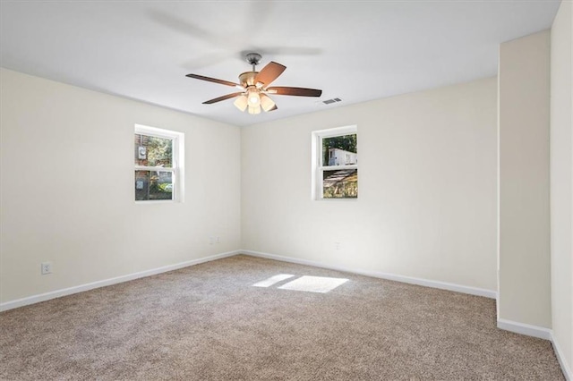 empty room featuring carpet floors, a healthy amount of sunlight, ceiling fan, and baseboards