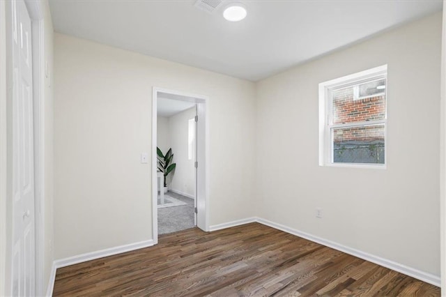 spare room with dark wood-style flooring and baseboards