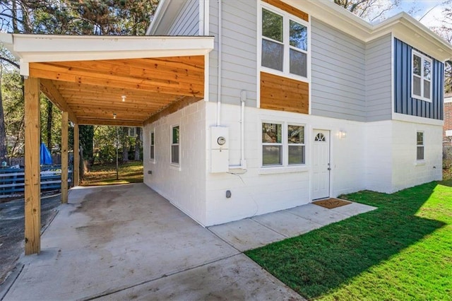 view of side of home featuring an attached carport, concrete driveway, and a lawn